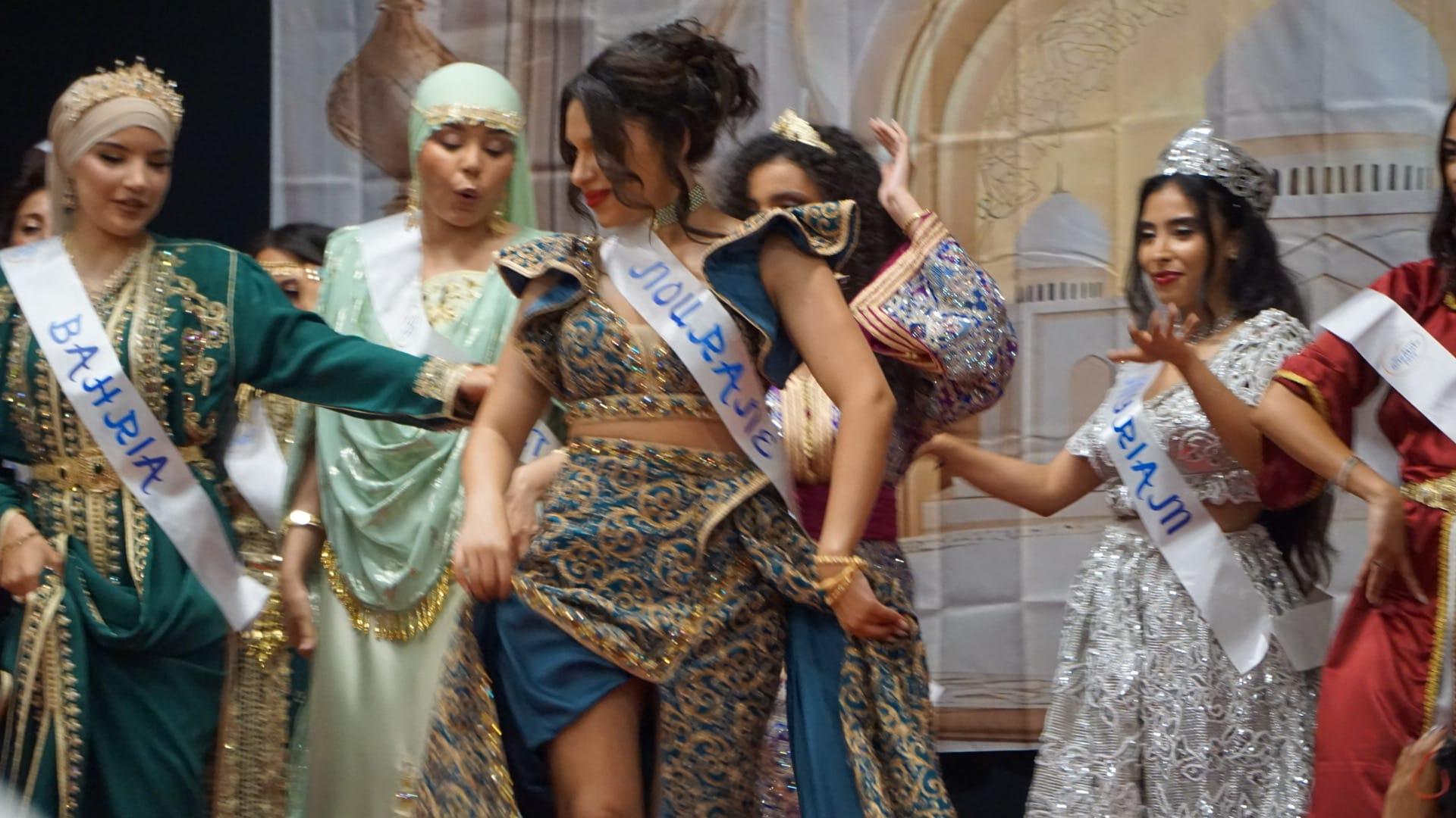 Les finalistes en caftans et robes brodées dansent devant le décor orientaliste de la scène.